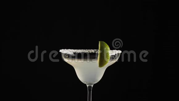 经典玛格丽塔鸡尾酒带有玛格丽塔酒的玻璃玻璃边缘有一片石灰在桌子中央旋转视频的预览图