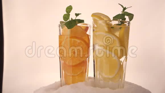 带柠檬水的杯子和雪中的橘子饮料视频的预览图
