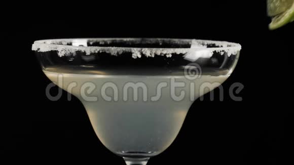 经典玛格丽塔鸡尾酒酒保拿了一片青柠用鸡尾酒放在杯子的咸边视频的预览图