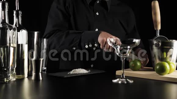 经典玛格丽塔鸡尾酒调酒师用钢刀在黑色背景的轻质木板上切割石灰视频的预览图