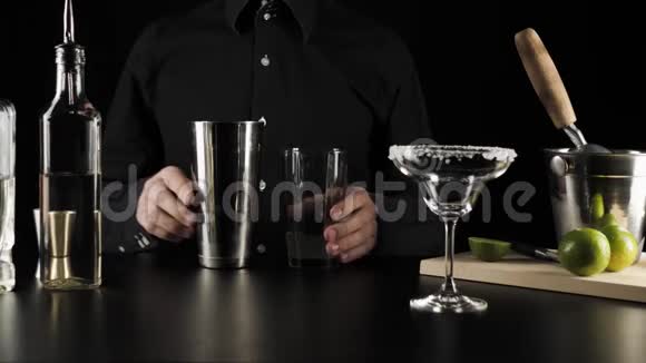 经典玛格丽塔鸡尾酒酒保将杯中的鸡尾酒倒入装有黑色背景冰块的摇床视频的预览图
