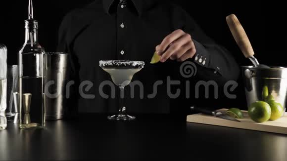 经典玛格丽塔鸡尾酒酒保拿了一片绿色的新鲜石灰用鸡尾酒放在杯子的边缘视频的预览图
