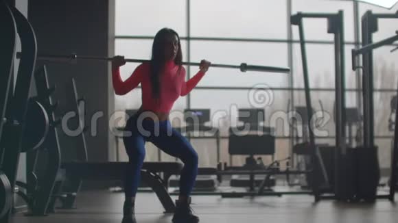 女孩在健身房里用杠铃蹲着视频的预览图