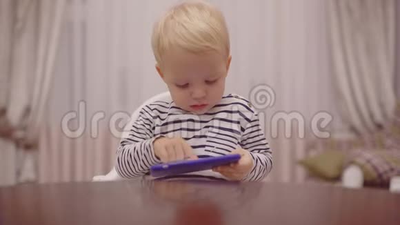 小男孩在厨房用智能手机吃早餐儿童手机智能手机迷为人父母视频的预览图