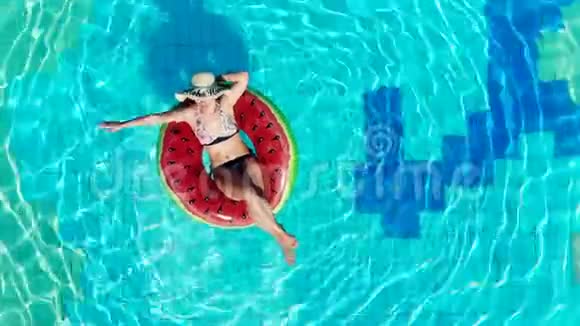 穿着泳衣的休息妇女漂浮在游泳池的橡胶圈上视频的预览图