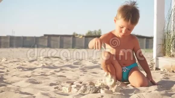 一个金发小男孩在沙滩上玩沙子视频的预览图