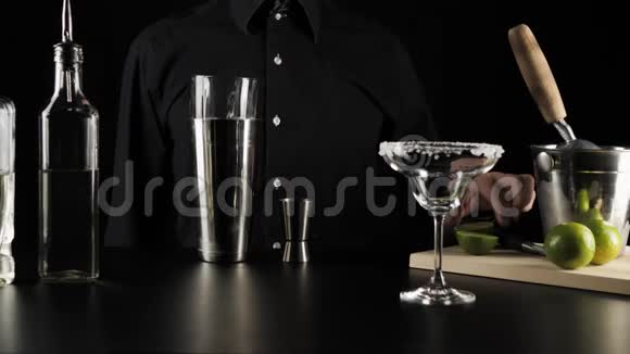 经典玛格丽塔鸡尾酒酒保拿着石灰在黑色背景下把石灰汁挤成一个跳汰机视频的预览图