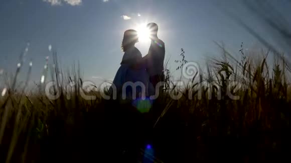 爱的男人和女人在明亮的阳光下亲吻田野的背景视频的预览图