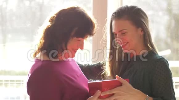 可爱的成年女儿向快乐的老母亲献上春花笑着拥抱年轻的女人视频的预览图