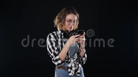 穿休闲服装的开朗女人格子衬衫和牛仔裤拿着智能手机在社交媒体或视频的预览图