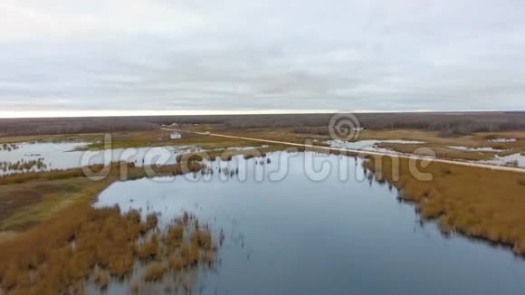 湖泊灌丛道路小聚落和多云地平线的空中镜头加拿大马尼托巴省北湖视频的预览图
