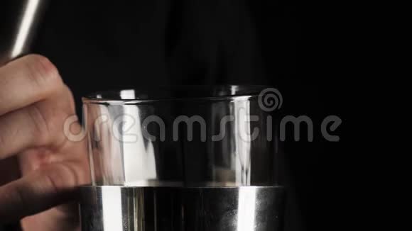 经典玛格丽塔鸡尾酒酒保把跳汰机上的石灰汁倒入黑色背景上有冰块的摇床视频的预览图