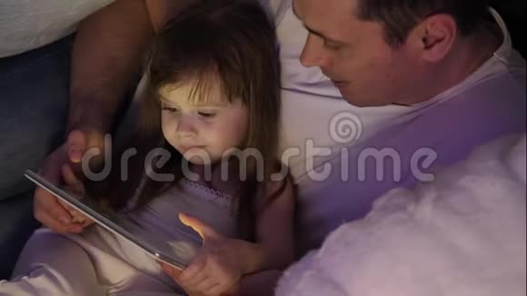 孩子和父亲在圣诞节晚上玩平板电脑在一个儿童房间与花环小女儿和爸爸视频的预览图