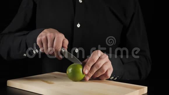 经典玛格丽塔鸡尾酒调酒师用钢刀在黑色背景的轻质木板上切割石灰视频的预览图