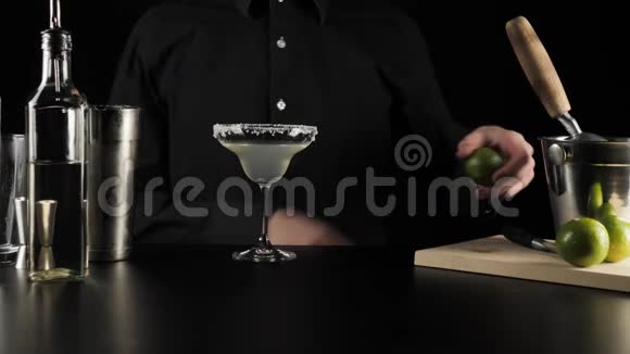 经典玛格丽塔鸡尾酒酒保拿着钢刀和青柠切下一块新鲜的青柠做装饰视频的预览图