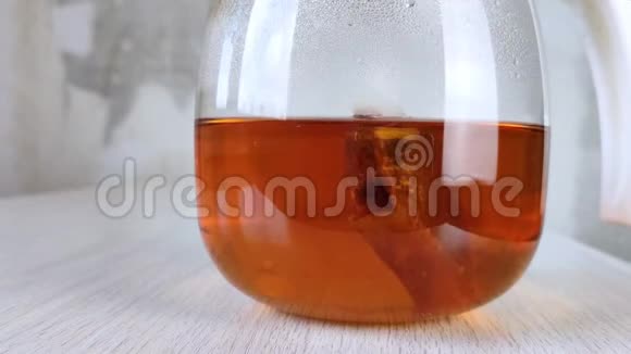 袋红茶用玻璃茶壶冲泡木桌上透明圆罐中的棕色琥珀饮料特写混凝土墙视频的预览图