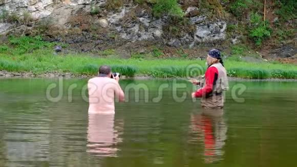 去钓鱼一个摄影师一个赤裸的躯干腰部深在水中拍摄一个渔夫穿着红色的衣服体育运动视频的预览图
