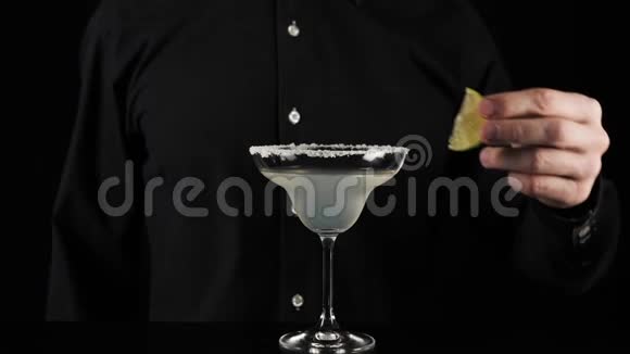 经典玛格丽塔鸡尾酒酒保拿了一片绿色的新鲜石灰用鸡尾酒放在杯子的边缘视频的预览图