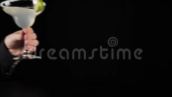 经典玛格丽塔鸡尾酒手在黑色背景的黑桌上放一杯玛格丽塔鸡尾酒玛格丽塔酒的概念视频的预览图