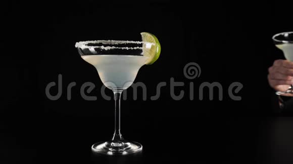 经典玛格丽塔鸡尾酒手把一个带有玛格丽塔鸡尾酒的玻璃杯放在黑色桌子上的黑色背景上视频的预览图