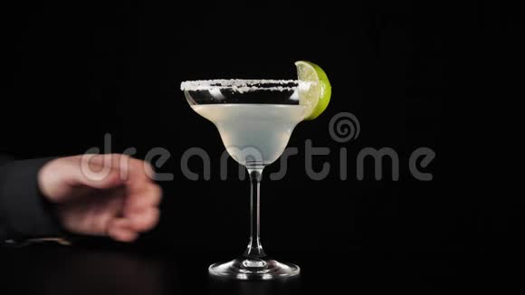 经典玛格丽塔鸡尾酒手拿一杯黑底黑桌上的玛格丽塔鸡尾酒视频的预览图