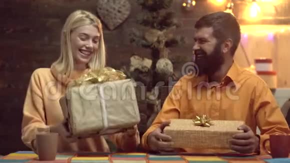 可爱的一对夫妇在家里打开圣诞礼物年轻夫妇把圣诞礼物包装成纸送礼物微笑视频的预览图