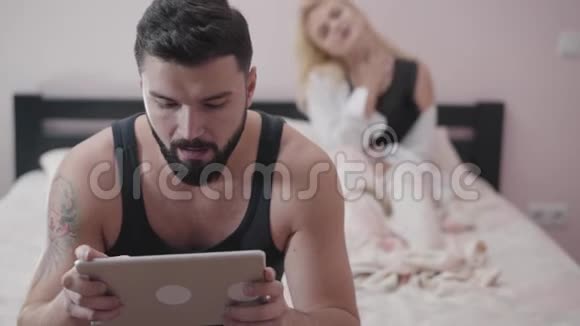 成年白种人坐在床上玩电子游戏的肖像性感的金发女人视频的预览图