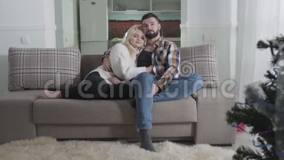 快乐白种人夫妻坐在沙发上拥抱的肖像恋爱中的情侣周末一起在视频的预览图