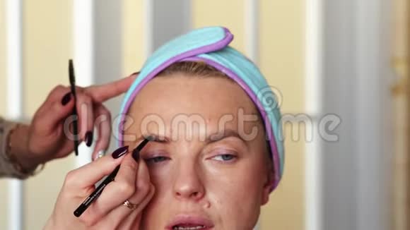 化妆师用铅笔给女孩画眉毛手术在家里进行视频的预览图