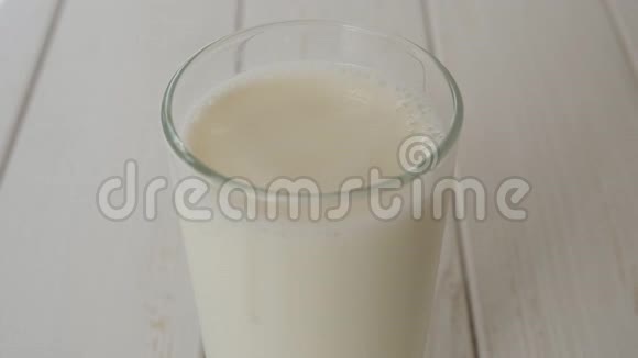在木制背景上特写一滴牛奶落入一杯牛奶视频的预览图