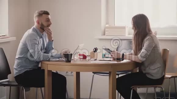 两个年轻的欧洲商人在现代光办公室的桌子旁严肃地交谈女老板来了视频的预览图