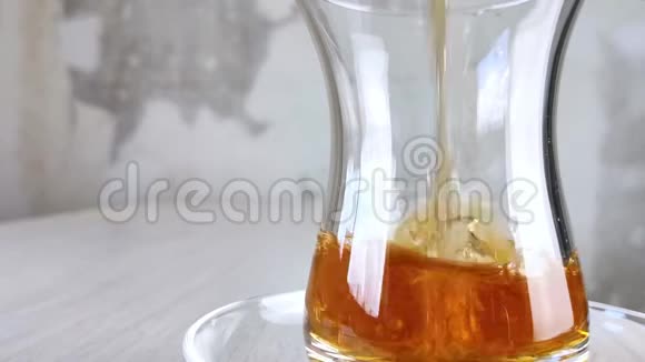 土耳其红茶倒入国杯在透明杯和木桌上的茶托中特写棕色饮料琥珀视频的预览图