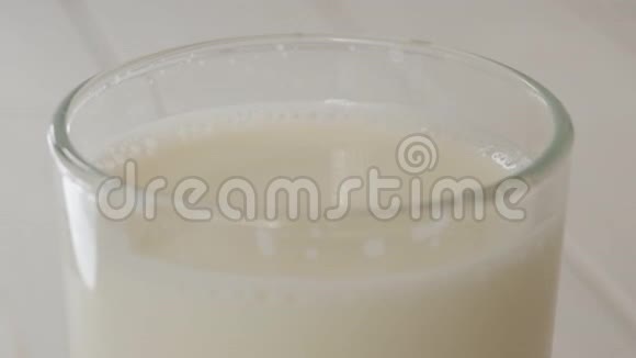 在轻木质的表面上滴入满杯牛奶的奶液视频的预览图