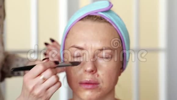 化妆师用画笔将粉底涂在女孩身上手术在家里进行视频的预览图