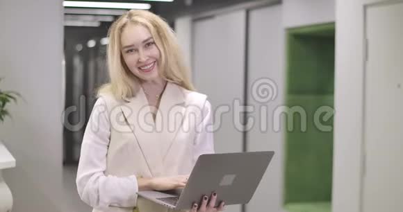 年轻迷人的高加索女人站在开放空间的办公室里看着相机微笑着成功视频的预览图