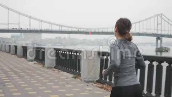年轻的运动女子身材瘦削早上在雾中沿河奔跑参加运动的女运动员很难视频的预览图