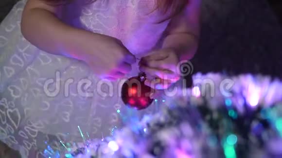 婴儿在圣诞树上挂一个红球快乐的童年概念小孩用圣诞节装饰圣诞树视频的预览图