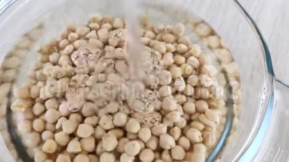 生的鹰嘴豆放在透明的玻璃碗里被水淹了用泡泡浸泡豆子近景烹饪健康食品视频的预览图