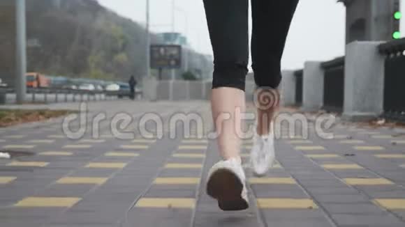 年轻女子脚穿着白色的专业跑鞋在沿河的城市码头上进行激烈的训练运动女运动员视频的预览图
