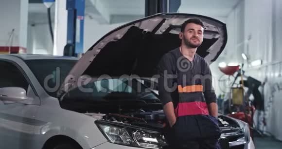 在一家汽车服务中心修理汽车时镜头前的帅哥笑得很有魅力视频的预览图