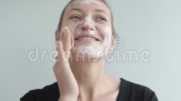一个漂亮的女人把泡沫放在皮肤上视频的预览图