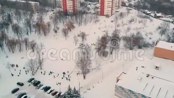 当孩子们骑在雪山上时可以俯瞰冬天的城市视频的预览图