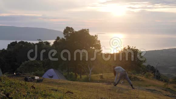一个女人在一个和平的自然露营地在山上做运动视频的预览图