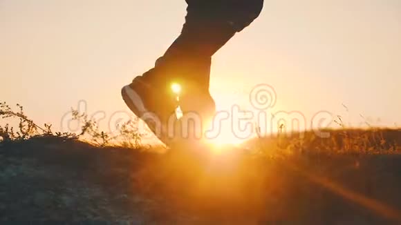徒步旅行者在日落时在岩石上散步穿着长途跋涉的靴子的腿沿着山脊走视频的预览图