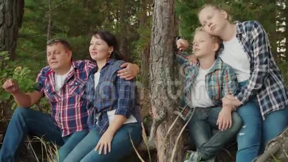 暑假快乐的一家人在针叶林拥抱母亲儿子父亲和女儿在松树上拥抱视频的预览图