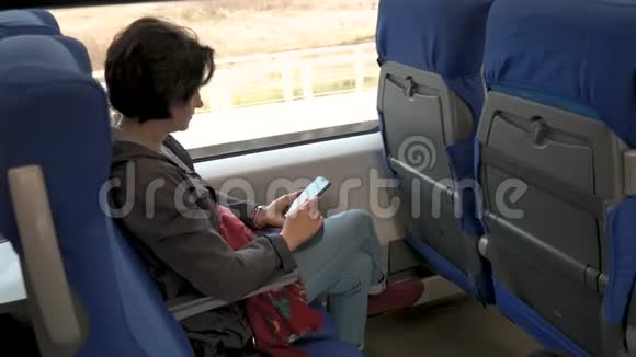 女人坐在火车上手里拿着手机点击后面的视线视频的预览图
