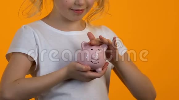 小女孩抚摸储蓄罐个人储蓄和预算规划未来视频的预览图