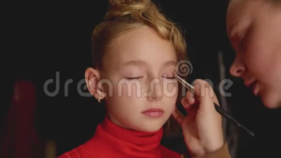 视觉师用刷子在眼睑时尚模特上涂抹眼影化妆师给少年女孩化妆视频的预览图
