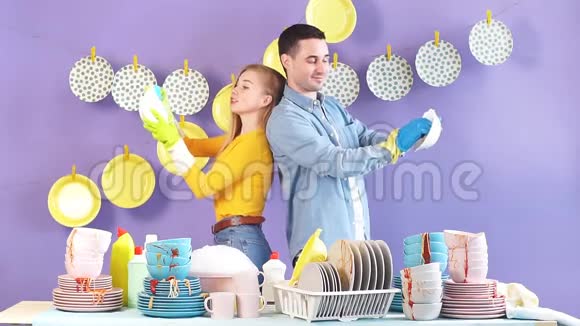 年轻积极快乐的一对夫妇背靠背站着洗碗视频的预览图