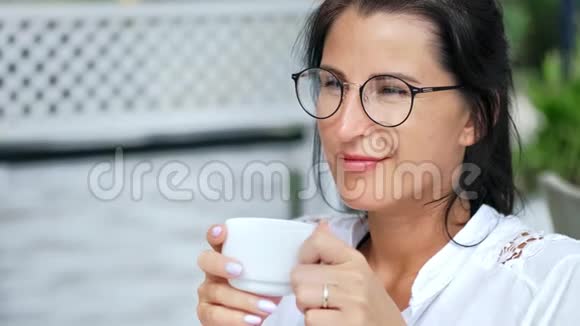 近距离微笑放松休闲的年轻女性在户外咖啡馆喝咖啡情绪积极视频的预览图